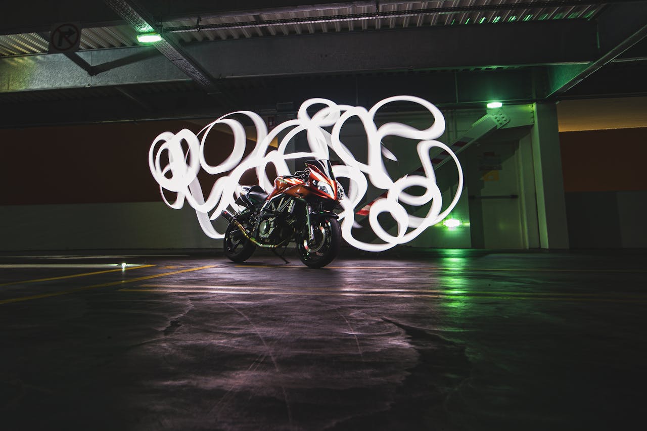 services-01 Creative light painting around a motorcycle in an illuminated underground parking garage at night.