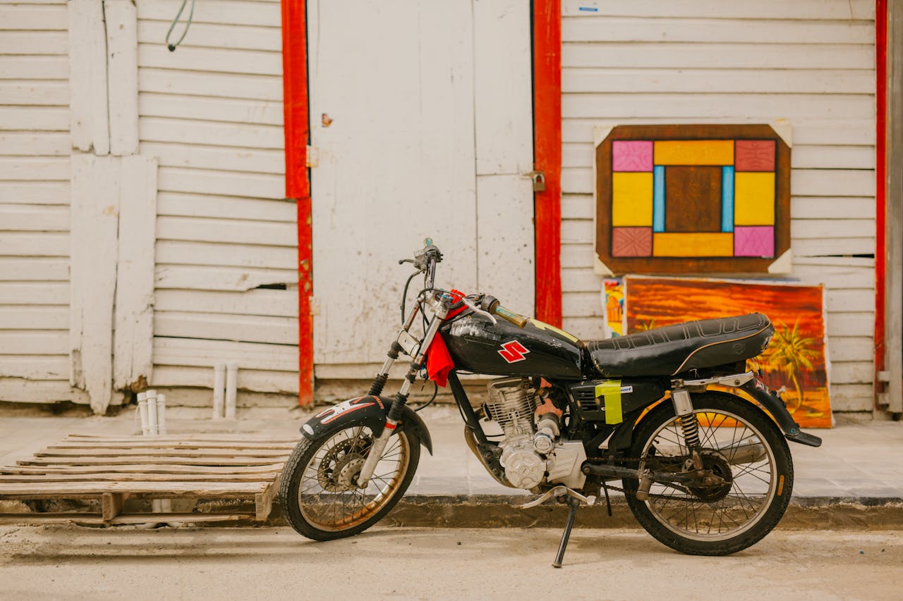 services-03 Classic motorcycle parked near a colorful vintage wooden door and artwork. Perfect for nostalgic themes.